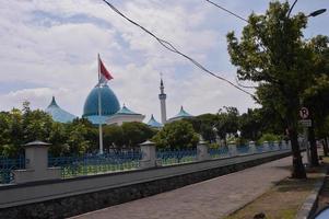 vista de la gran mezquita con la cúpula y la bandera indonesia delante. foto