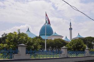 vista de la gran mezquita con la cúpula y la bandera indonesia delante. foto