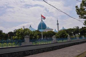 view of the grand mosque with the dome and the Indonesian flag in front of it. photo