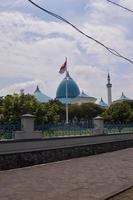 vista de la gran mezquita con la cúpula y la bandera indonesia delante. foto