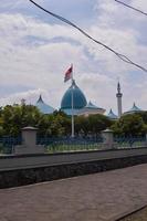 vista de la gran mezquita con la cúpula y la bandera indonesia delante. foto