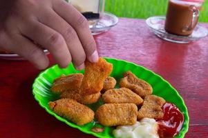 the hand holding the nugget. Delicious crispy breaded chicken nuggets. photo