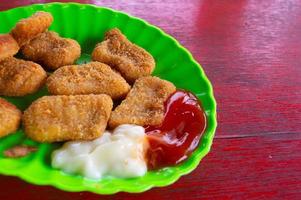 nuggets on a green plate that sits on a wooden table photo