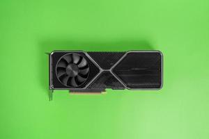 Modern graphic card on green surface. Massive radiator with two coolers. Modern gaming and rendering graphics card. Top view, flat lay photo