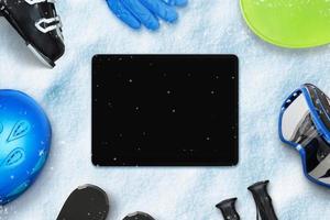 Blank tablet on snow surrounded by ski equipment. Blank screen for copy or web page design promotion photo