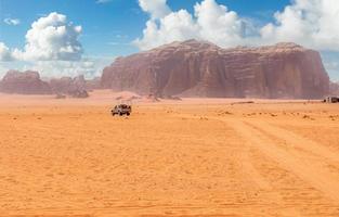 Orange sands and cliffs of Wadi Rum desert with tourist car in the background, Jordan photo