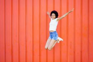 mujer negra despreocupada saltando cerca de la pared foto