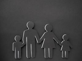 A human symbol made of black paper on a black background. Concept of family. Mom, dad, daughter and son photo