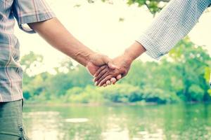 Asian elderly couple holding hands together, love each other and take care of each other forever. The backdrop is a beautiful natural river. photo