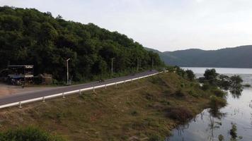 embalse de muak lek en saraburi desde la vista aérea de pájaro. hermosa naturaleza invisible en la presa de muak lek con carretera al lado con agua y colina de árboles. video