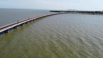 vista aérea de un increíble tren de viaje estacionado en un puente ferroviario flotante sobre el agua del lago en la presa pa sak jolasid con cielo azul en lopburi, tailandia. video