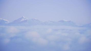 tiro de lapso de tiempo de nubes voladoras entre picos de montaña nevados durante el día soleado video