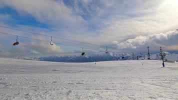 Static timelapse of open chair lifts in fast motion on cable rope with skiers in snowy day. Ski resort reopens. Georgia winter holidays in Gudauri. Sunny day fun on fresh snow video