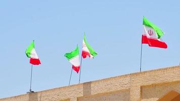 Many iranian flags wave in wind on rooftop of building