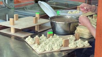 Close up table with raw meat khinkali on display on preparation by woman. Traditional georgian cuisine and food preparation traditions in caucasus video