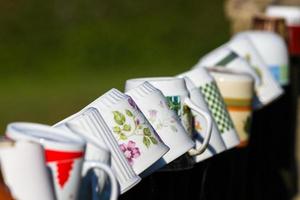 a row of coffee mugs stacked on the fence photo