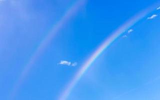 hermoso arco iris doble raro en el fondo azul cielo nublado méxico. foto