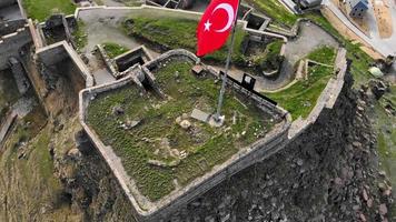 gros plan aérien survoler le drapeau au sommet du château de kars en turquie. patrimoine historique turkiye