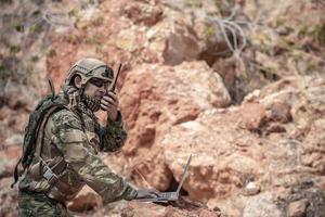 soldados de fuerzas especiales en guerras en el desierto, gente de tailandia, soldado del ejército usan una computadora portátil para ver el mapa con satélite, usan radio para comunicarse durante la operación militar foto