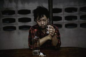 Asian man drink vodka alone at home on night time,Thailand people,Stress man drunk concept photo