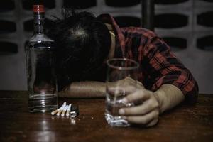 hombre asiático bebe vodka solo en casa por la noche, gente de tailandia, concepto de borracho de hombre estresado foto