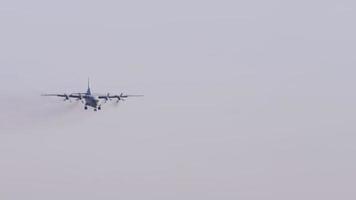 Military transport aircraft descends on landing, side view. Four propeller airliner flies video