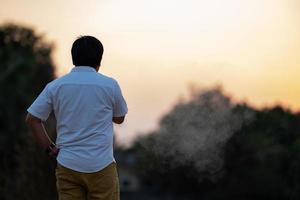 Asian man is smoking backside in the twilight time. photo