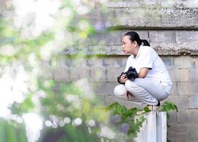 Asian Professional cameraman sits and thinks about how to create a creativity photo in the construction area background and environment.