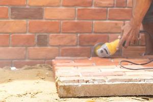 Focus on the polyurethane foam Brick wall on the floor with blur worker hand and grinder machine behind. photo