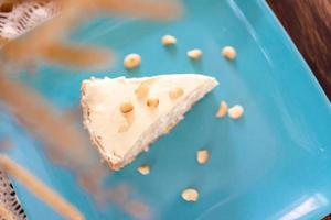 Coconut Cream Pie in the turquoise dish on the wood table that topping with macademia. Shooting in the sunlight. photo