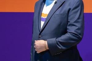 Close up to the body of smart caucasian big guy, a confident business man in front of orange and purple background. photo