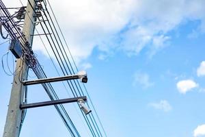 cctv camera is installed on the Metal stick that hung on to electric pole beside the street in village for monitoring and running safety system control in that area. photo