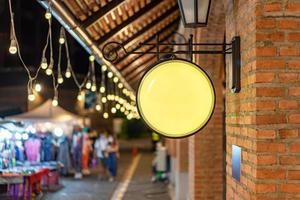 The Circle yellow Lightbox has hung on the wall in front of the brick pole in a Tungsten ambient environment vintage shopping community mall. photo