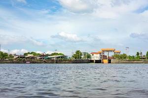 río chao phraya en el día de cielo abierto con el pueblo, el templo y el edificio local. dispárale en el bote desde el medio del río. foto