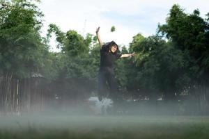 Asian short hair Woman is Joyful Jumping in the fog environment on grass field garden. photo