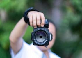 Asian man holds the Medium Format Camera in his hand and focus to shoot in front of him. photo