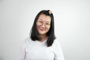 la mujer asiática de las gafas está mirando y sonriendo a la cámara y de pie sobre fondo blanco en la luz del estudio. foto