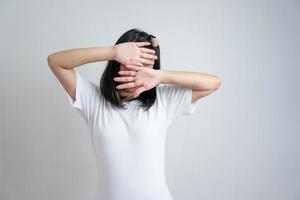 Young Asian glasses girl rises up her arms to cover her face in studio light white clear background. photo