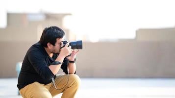 el camarógrafo profesional asiático mira el visor de la cámara y se enfoca en la vista para tomar una foto en el campo al aire libre en la azotea.
