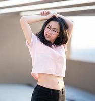 Beautiful Glasses Asian woman raise her hand up and poses for an image at outdoor rooftop building environment. photo