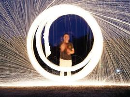Spinning and burning Steel wool sparkle fire in the circle shape with long speed shutter shoot glowing light line to the ground. photo