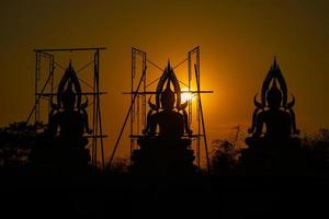 siluetee la estatua de buda entre la creación y el proceso de construcción, en el campo al aire libre con la puesta de sol y el período de crepúsculo, tailandia. foto