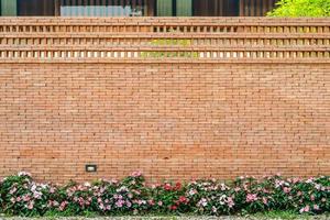 The backdrop of Brick wall with pink - white flower on the bottom for architecture and nature combination background story. photo