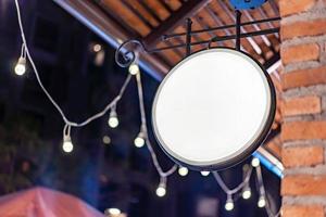 The Circle white Lightbox has hung on the wall in front of the brick pole in a Tungsten ambient environment vintage shopping community mall. photo