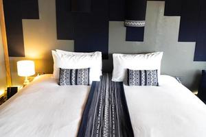 cama blanca moderna y almohada azul oscuro combinación de estilo asiático de dormitorio de madera vintage. foto