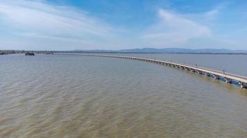 Aerial view of an amazing travel train parked on a floating railway bridge over the water of the lake in Pa Sak Jolasid dam with blue sky at Lopburi, Thailand. photo