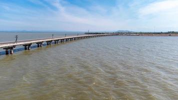 Aerial view of an amazing travel train parked on a floating railway bridge over the water of the lake in Pa Sak Jolasid dam with blue sky at Lopburi, Thailand. photo