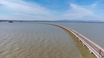 Aerial view of an amazing travel train parked on a floating railway bridge over the water of the lake in Pa Sak Jolasid dam with blue sky at Lopburi, Thailand. photo