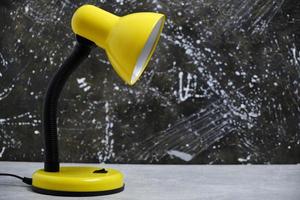 Bright yellow table lamp background concrete wall.