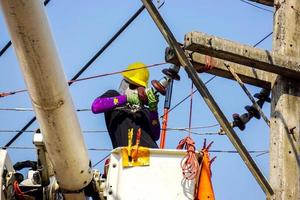 electricistas de primer plano que trabajan en el teleférico para reparar la línea eléctrica bajo un fondo de cielo azul claro. foto